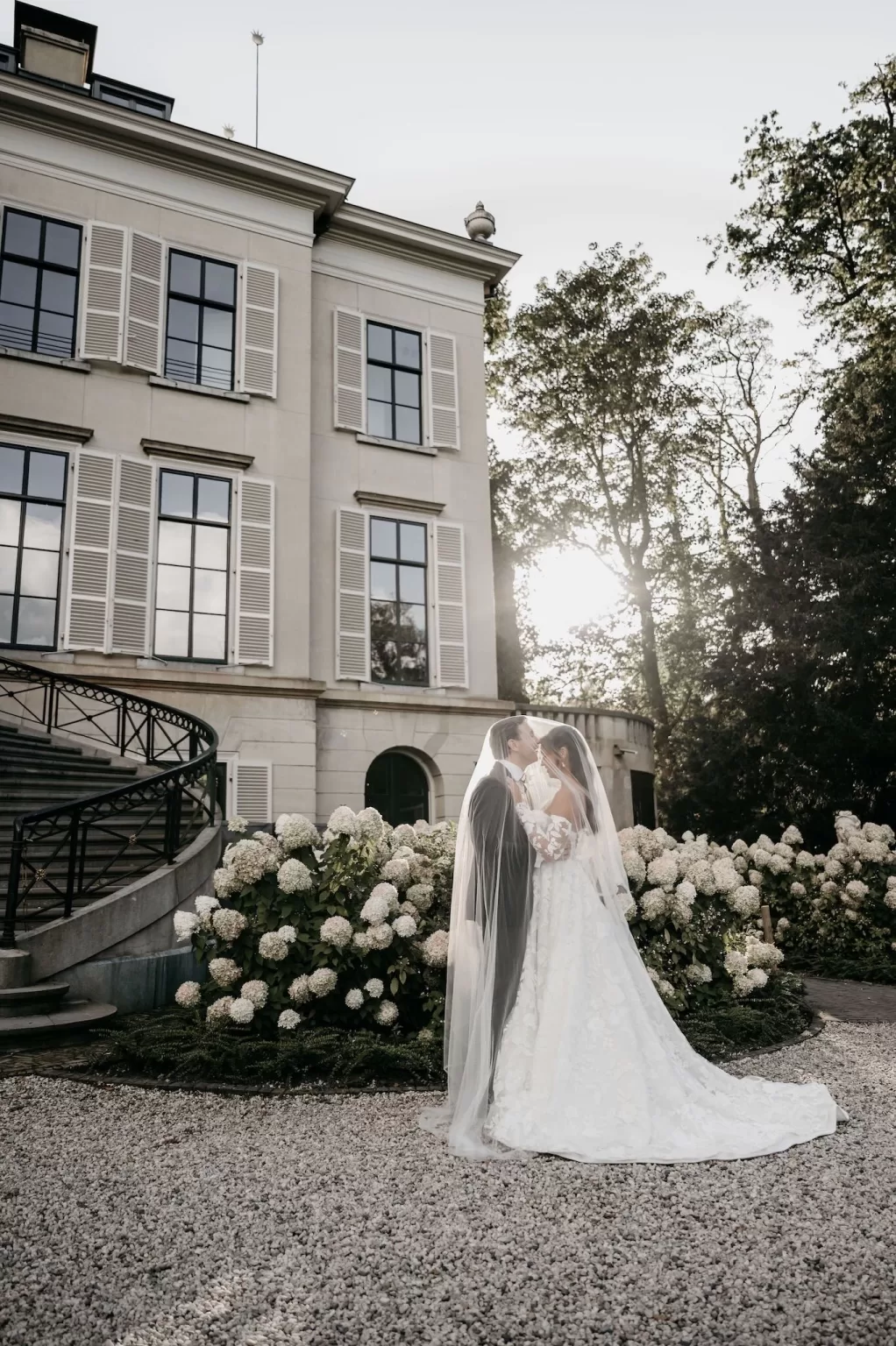 Romantic kiss under the bride’s veil in the garden of Parc Broekhuizen.
