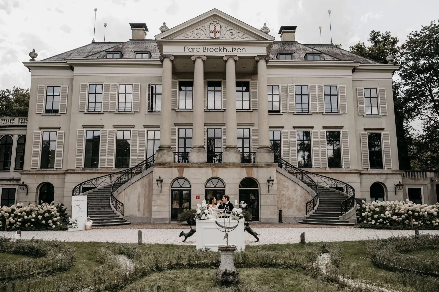 Grand facade of Parc Broekhuizen with newlyweds celebrating in front of the entrance.