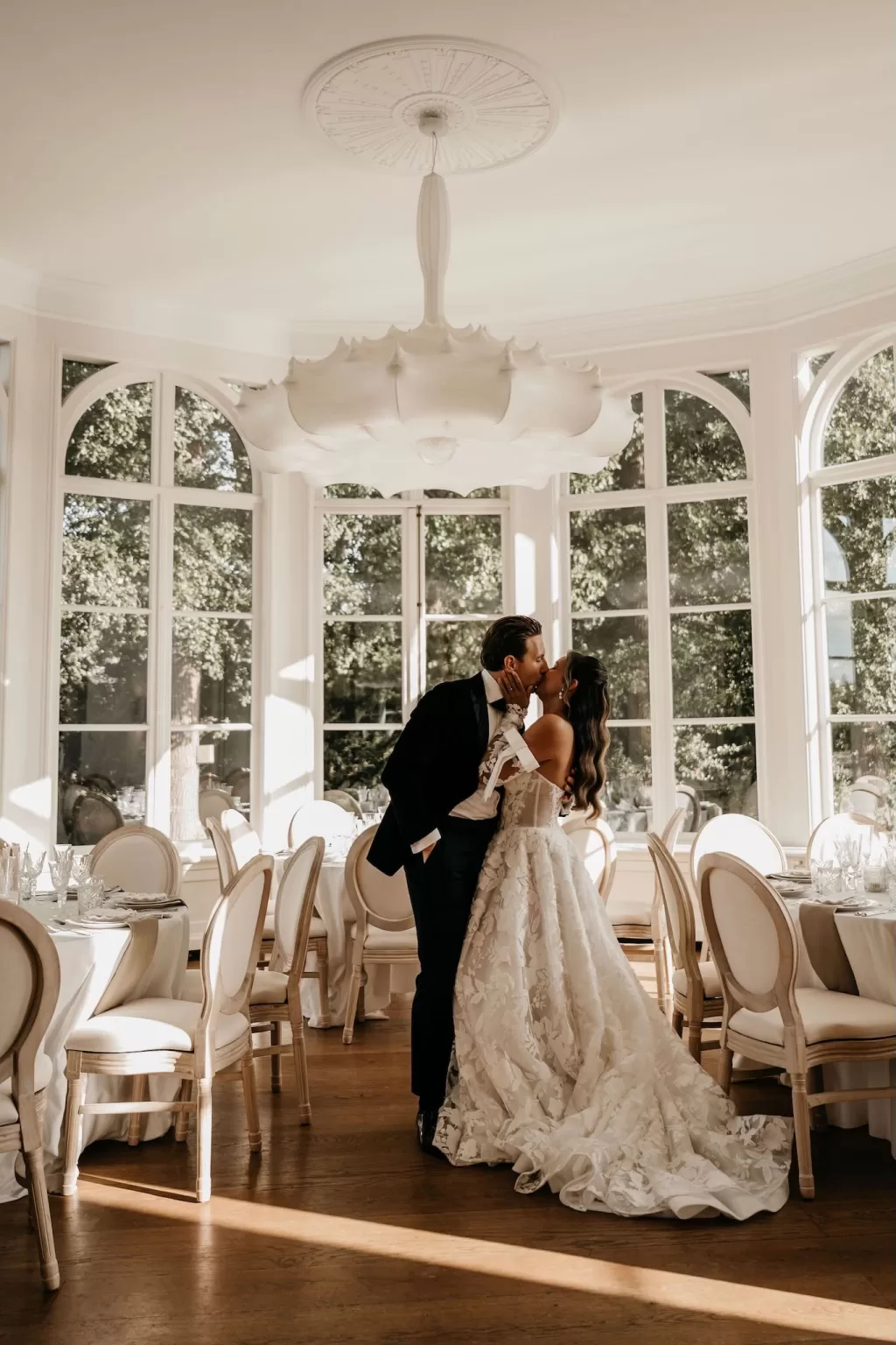 Bride and groom share a kiss in the light-filled reception room at Parc Broekhuizen.