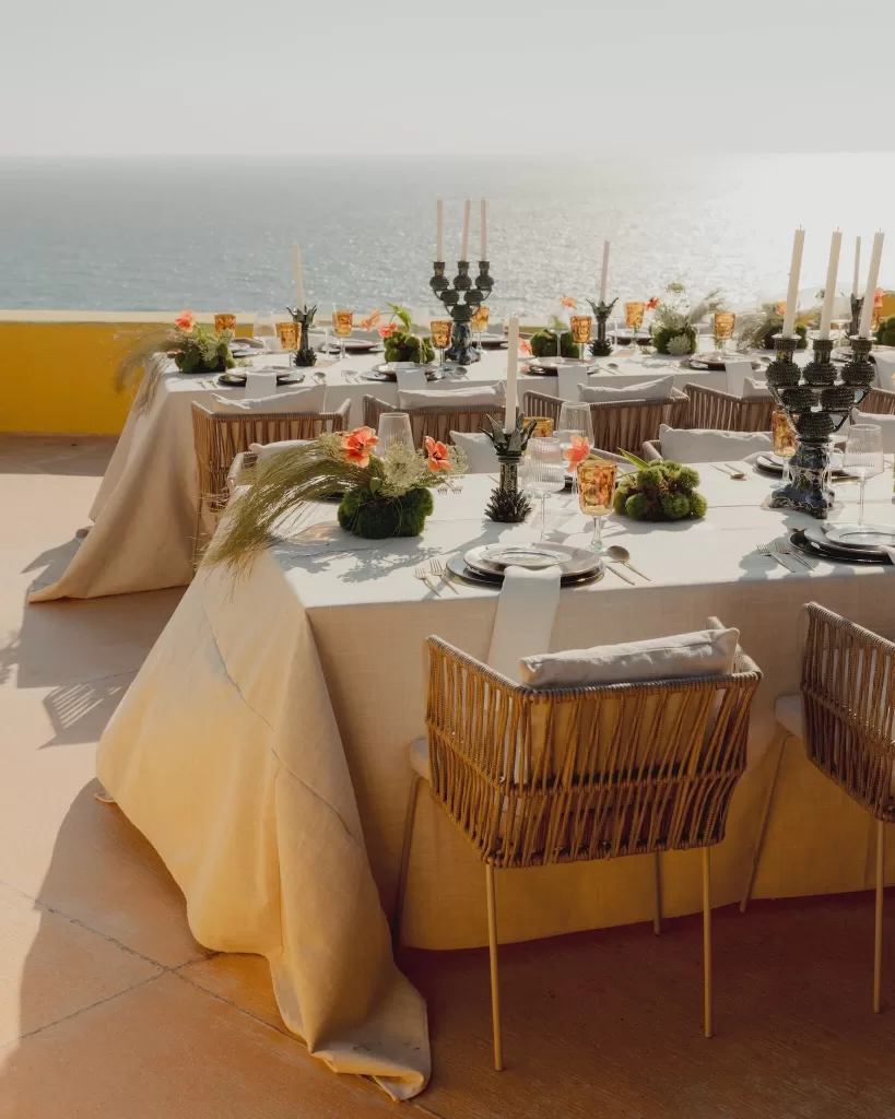 Wedding reception tables styled with candles and flowers overlooking the shimmering sea.