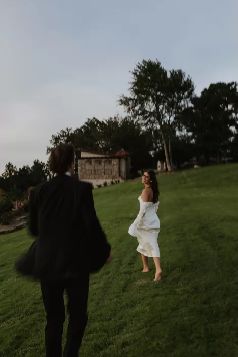Groom chasing his bride across the green lawn with Stone Haven’s villa in the background.