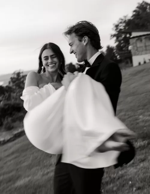Groom carrying his smiling bride across the lawn in a candid moment at Stone Haven.