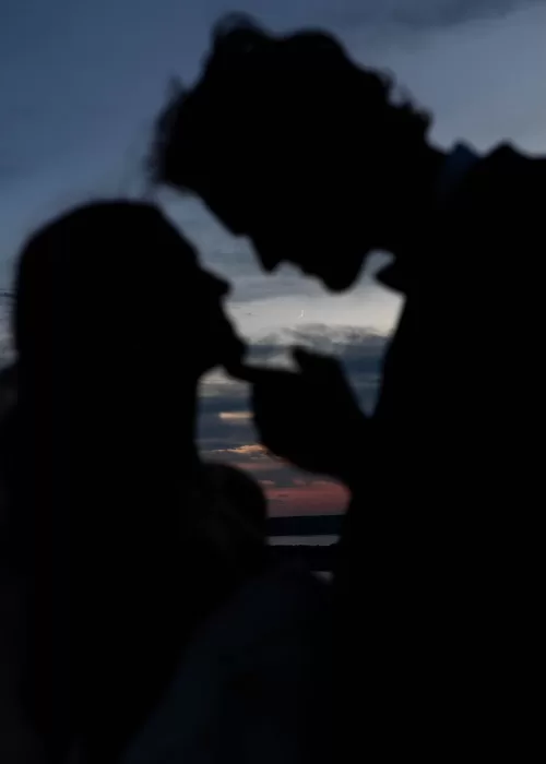 Silhouette of the couple leaning in for a kiss with a colorful sunset sky at Stone Haven.