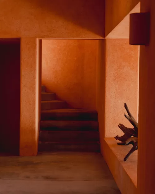 Narrow staircase framed by terracotta walls with soft afternoon light and shadows.