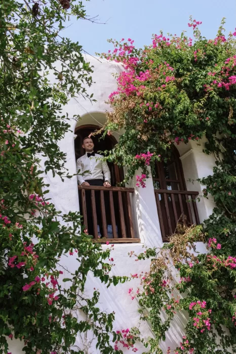 Groom standing on a whitewashed balcony framed with bougainvillea at Villa Blue Star Ibiza.