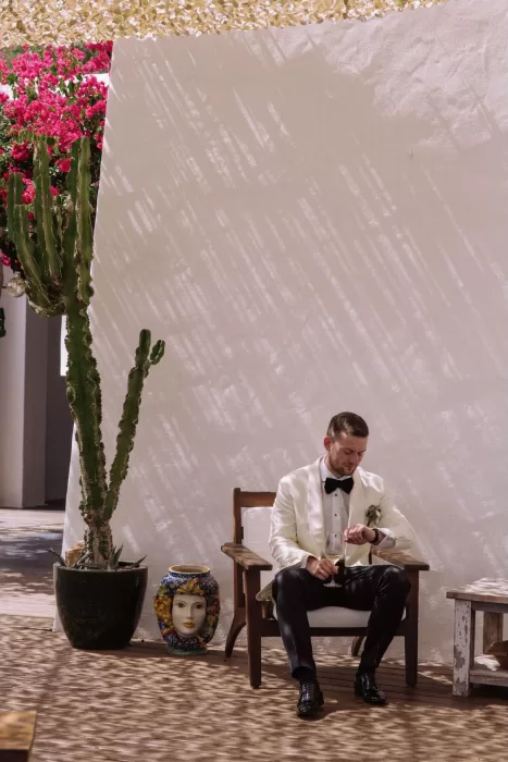 Groom in a white tuxedo jacket relaxing in shaded courtyard at Villa Blue Star Ibiza.