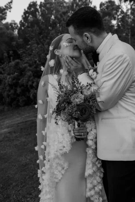 Bride and groom share a tender kiss under a floral veil at Villa Blue Star Ibiza.