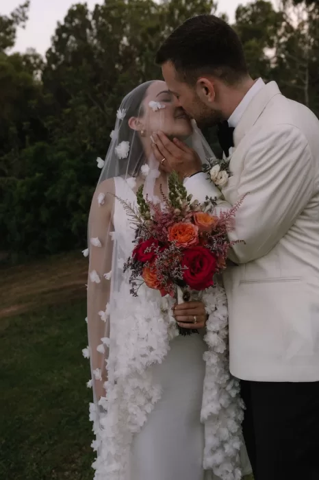 Groom tenderly kissing bride beneath her floral veil at Villa Blue Star Ibiza.