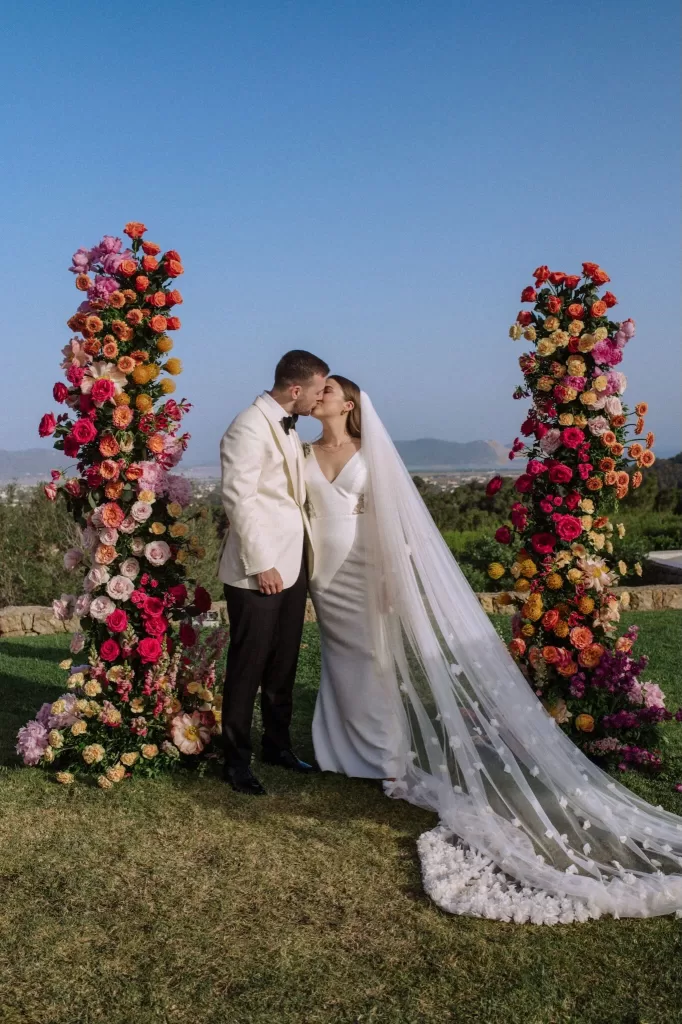 Bride and groom share a kiss framed by floral pillars at Villa Blue Star Ibiza.