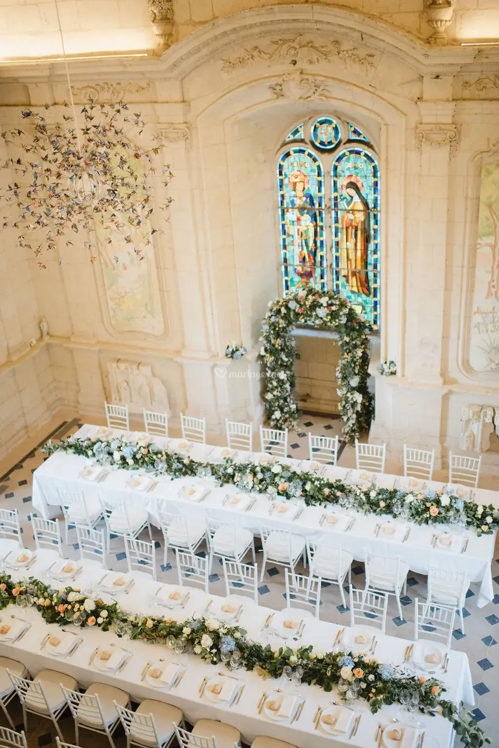 Floral-decorated chapel at Château de Jalesnes transformed into an elegant wedding reception space with white tables and greenery.