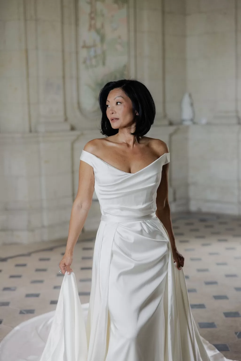 ride holding the train of her satin gown while standing in the softly lit chapel of Château de Jalesnes.