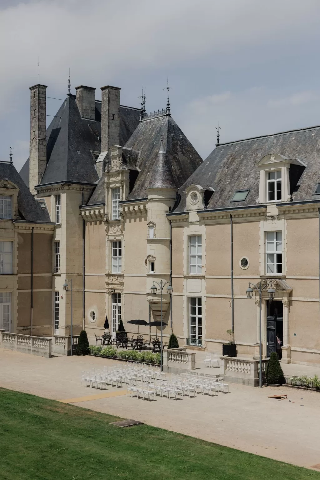 Outdoor ceremony setup with white chairs arranged in front of Château de Jalesnes under soft afternoon light.