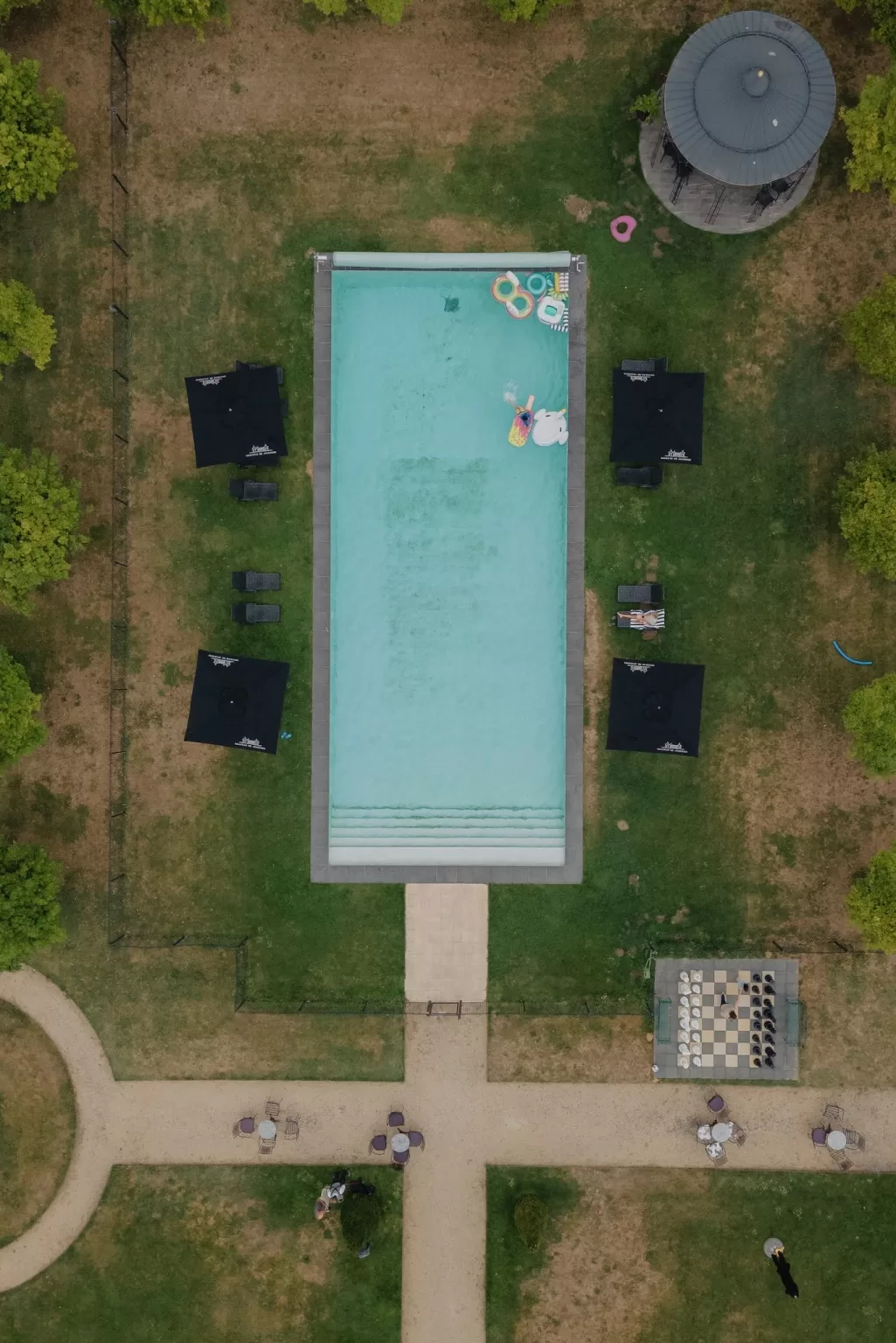 Aerial view of Château de Jalesnes swimming pool surrounded by garden paths and shaded seating.