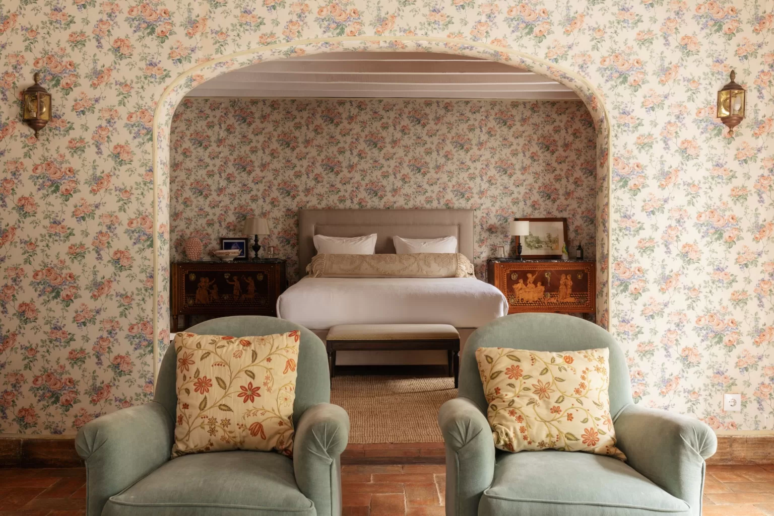 Elegant master bedroom at Herdade do Peru with floral wallpaper, soft armchairs, and classic Portuguese decor.
