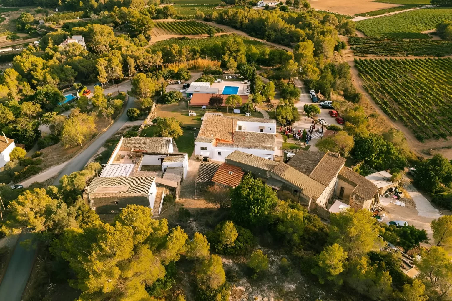 Aerial view of Masia Can Ramonet surrounded by vineyards and countryside in Catalonia.