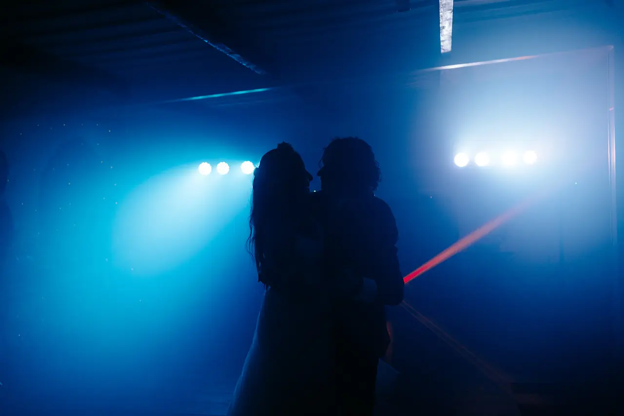 Couple sharing their first dance under blue lights at Masia Can Ramonet, creating a romantic and cinematic atmosphere.