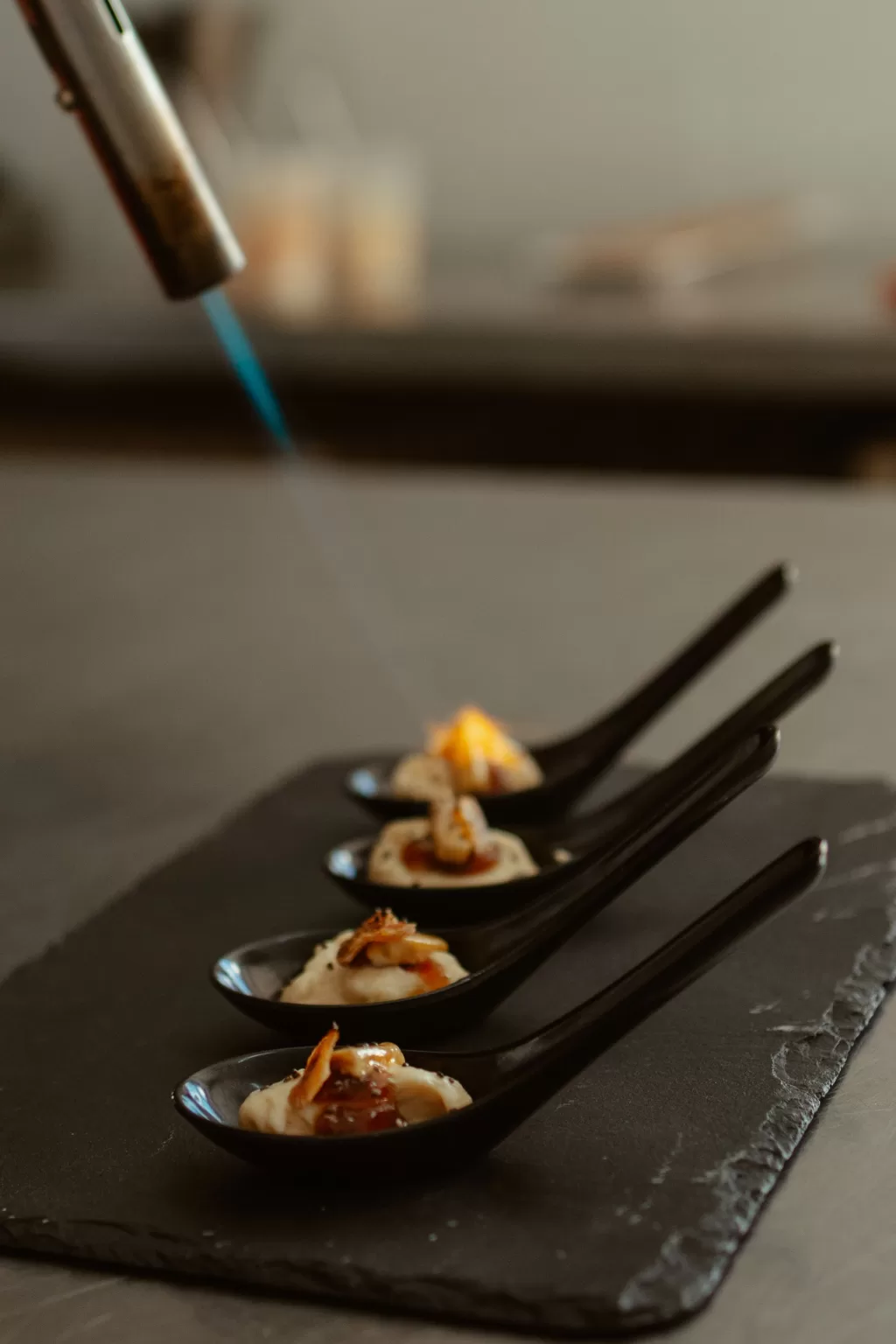 Gourmet wedding appetisers being flame-torched by a chef at Masia Can Ramonet.