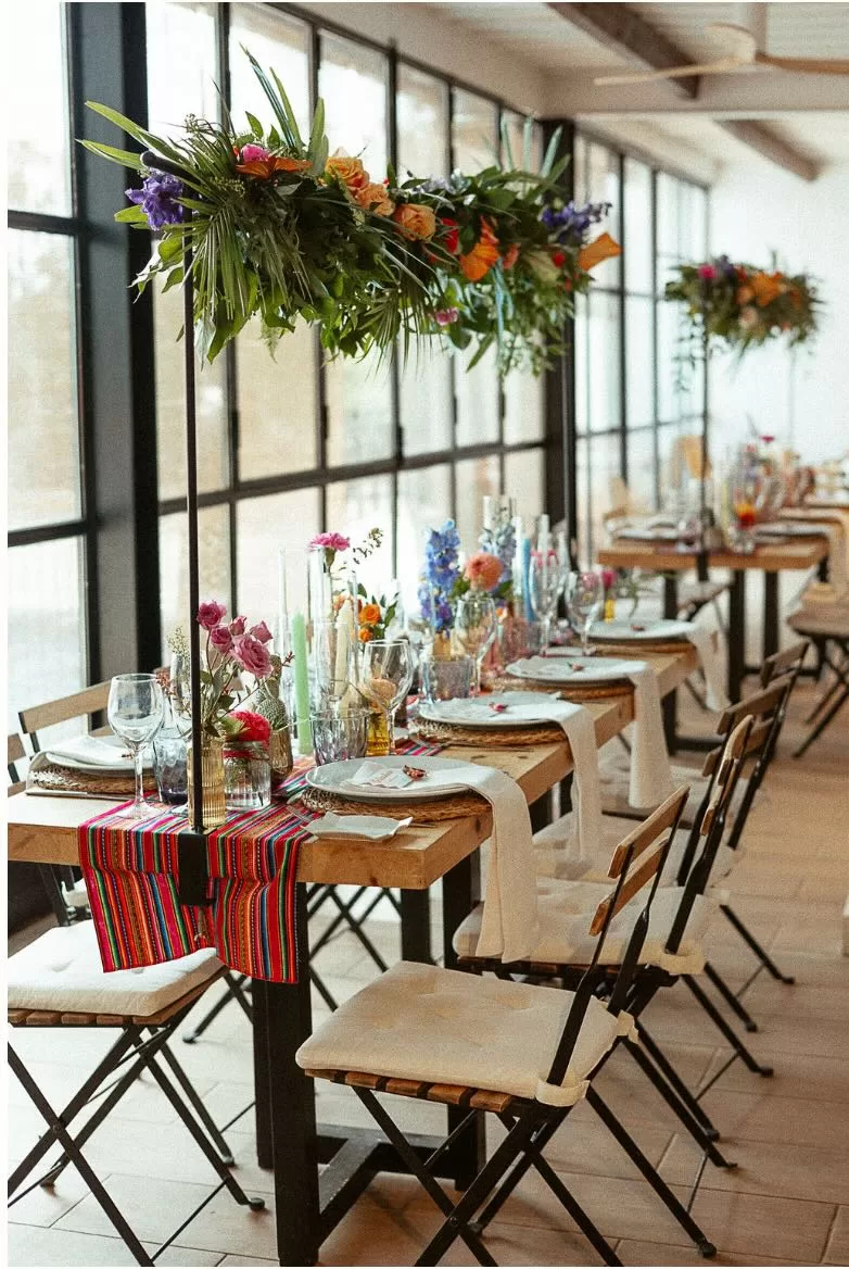Indoor wedding table styling at Masia Can Ramonet featuring hanging florals and vibrant décor.