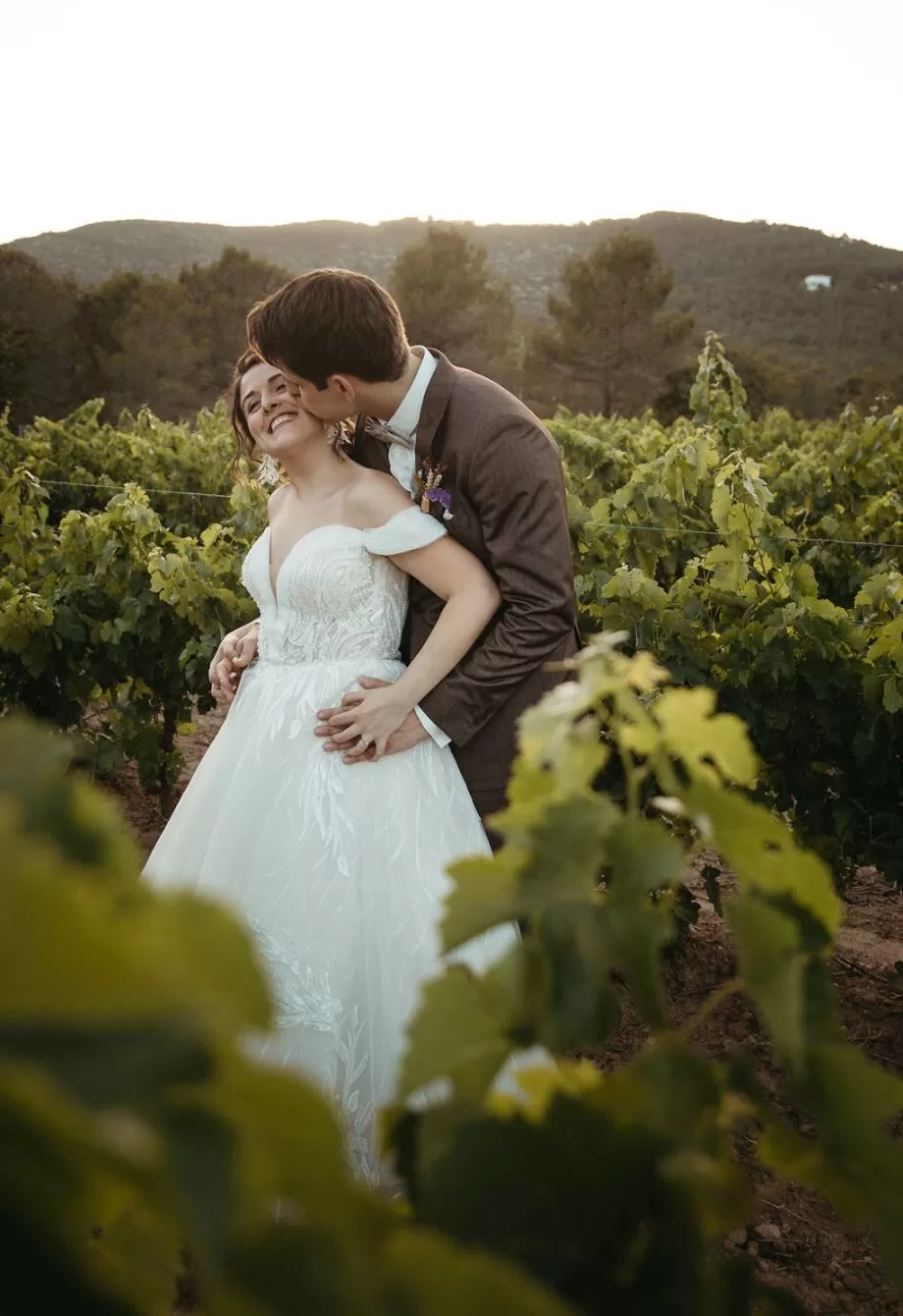 Newlyweds standing beneath the floral arch in the vineyard at Masia Can Ramonet.
