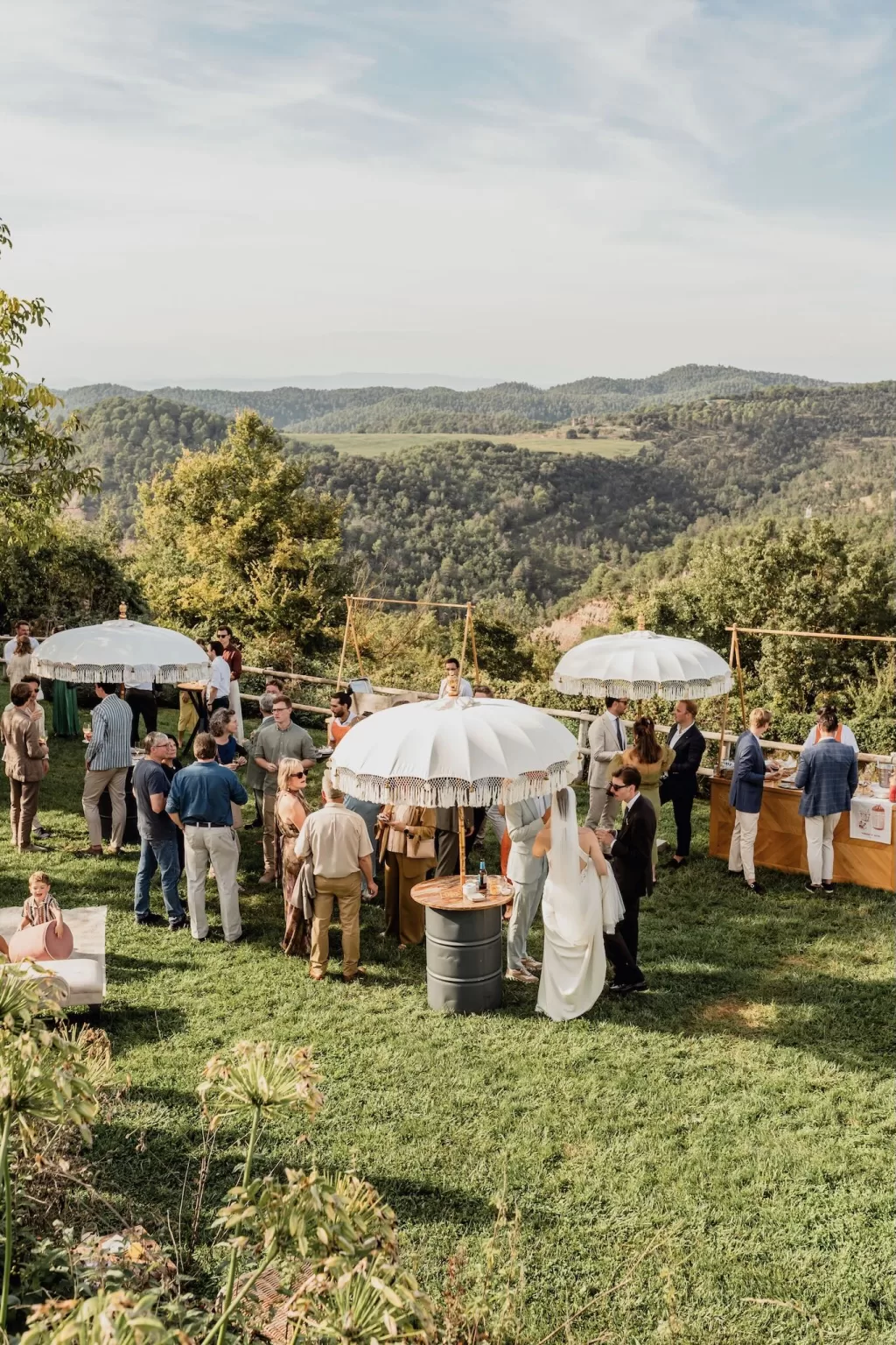 Guests mingling under white umbrellas overlooking rolling hills during the outdoor wedding reception at This Must Be The Place.