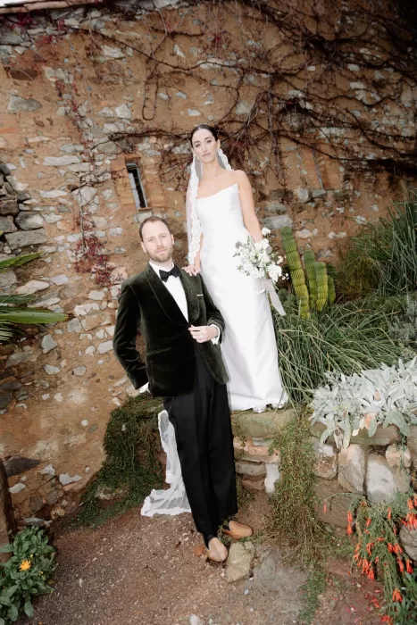Bride and groom posing elegantly by a rustic stone wall at This Must Be The Place wedding venue.
