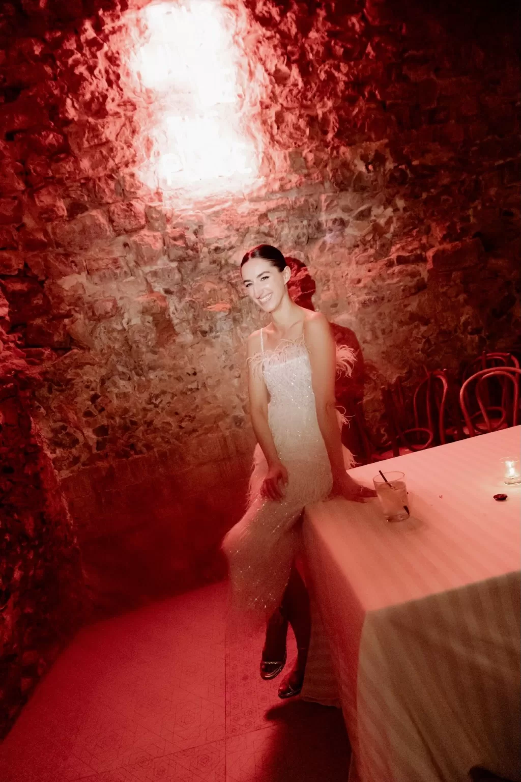 Bride enjoying the after-party in red lighting inside the stone-walled cellar of This Must Be The Place.