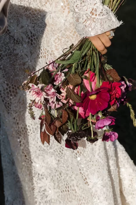 Detail of the bride’s vibrant bouquet against her lace wedding gown at Areias do Seixo.