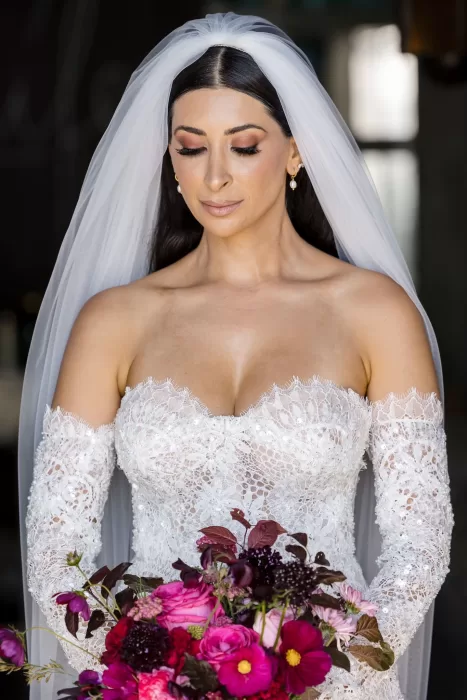 Close-up bridal portrait at Areias do Seixo, with the bride holding a vivid berry-toned bouquet.