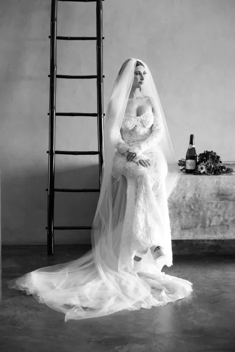 Elegant bridal portrait at Areias do Seixo, with the bride seated in a lace gown and long veil beside a rustic ladder.