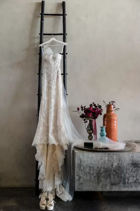 Wedding dress displayed on a black ladder at Areias do Seixo, styled with florals and delicate décor.