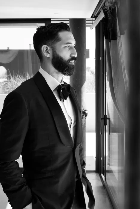 Groom’s black-and-white portrait at Areias do Seixo, standing by a window with soft natural light.