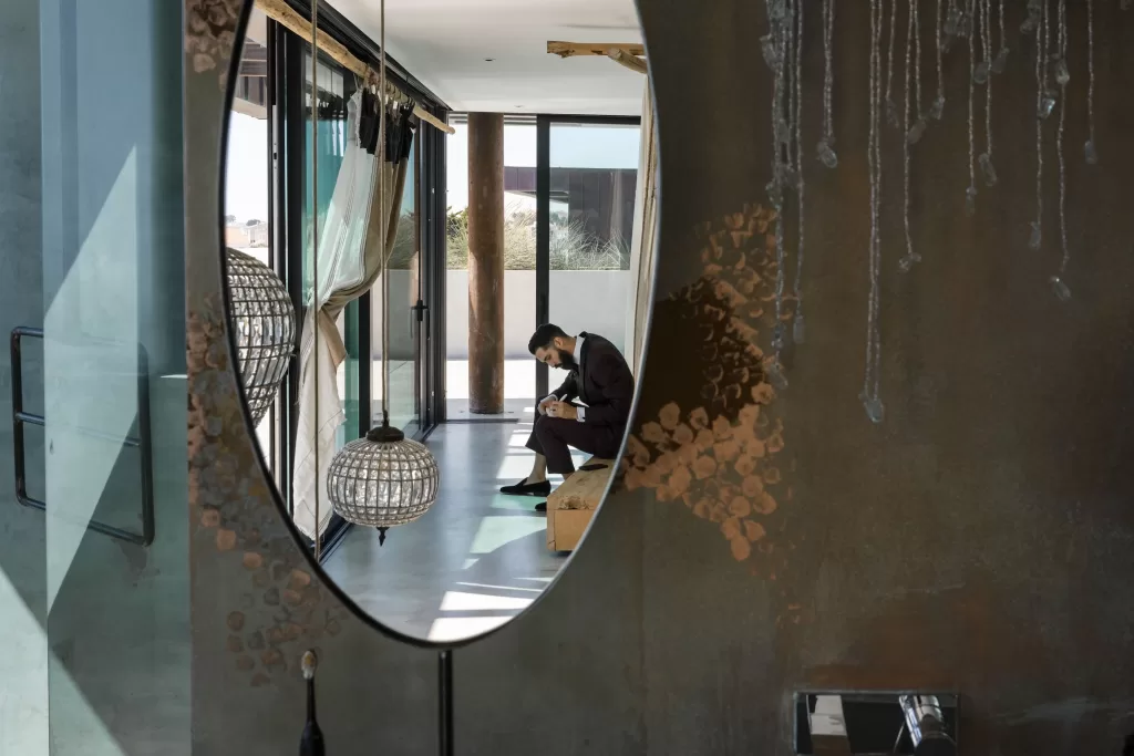 Groom writes a note quietly inside Areias do Seixo, reflected through artistic interior mirrors.