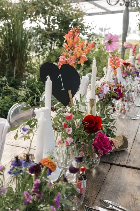 Colourful garden-inspired wedding table setting at Areias do Seixo, filled with vibrant flowers and tall white candles.