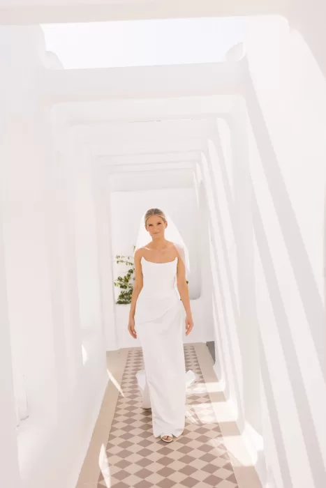 Bride walking through the bright white geometric corridor at Casa Arte, her gown glowing in the natural light.