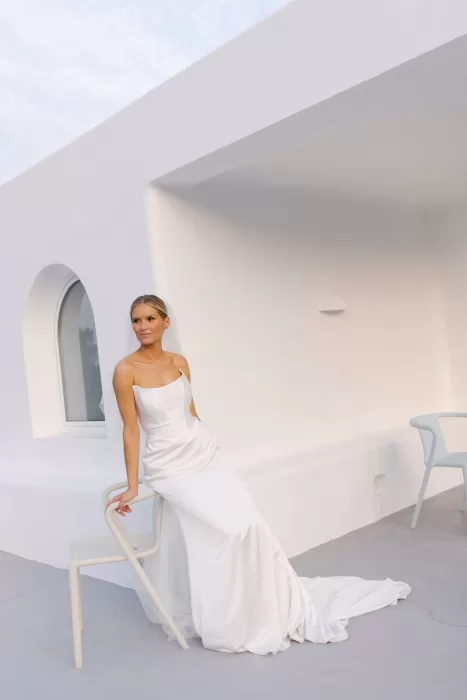 Bride posing on the modern white terrace at Casa Arte during golden hour, her gown flowing softly behind her.
