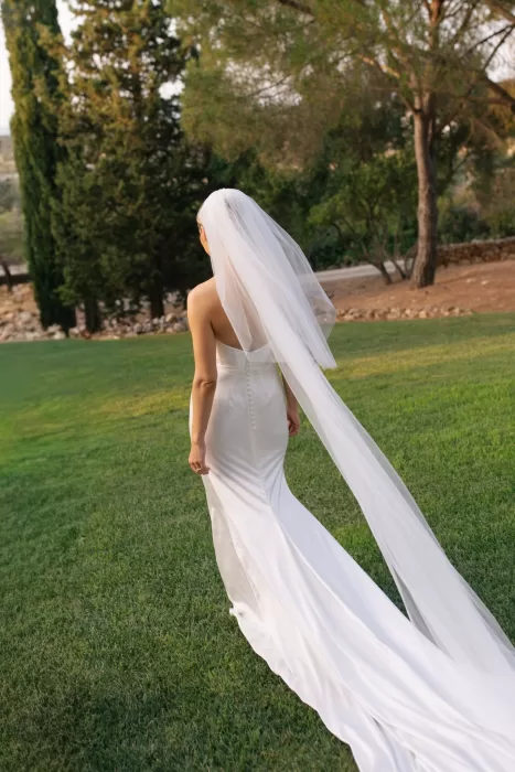 Bride walking across the lawn at Casa Arte, her long veil and gown trailing behind her in the golden evening light.