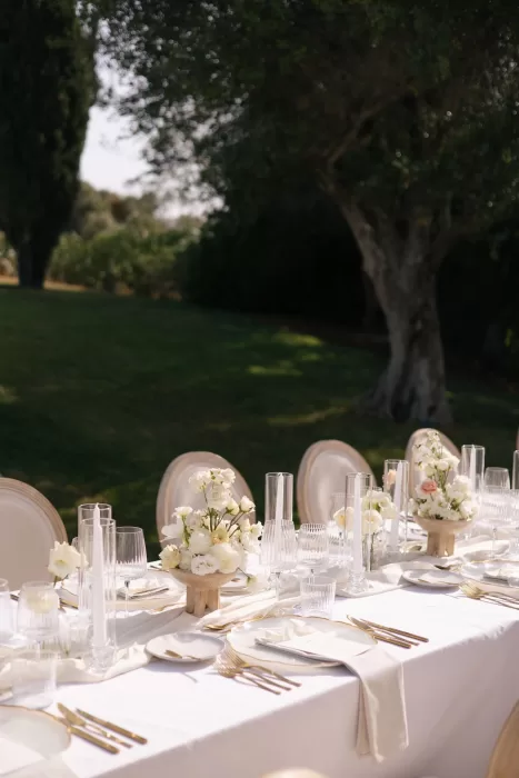 Elegant outdoor table at Casa Arte decorated with white florals, clear glassware, and soft neutral linens.