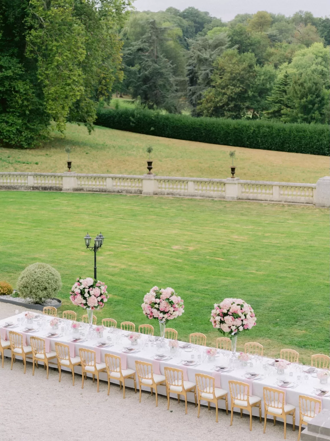 Long outdoor banquet table at Château Bouffémont overlooking expansive green lawns and surrounding woodland.