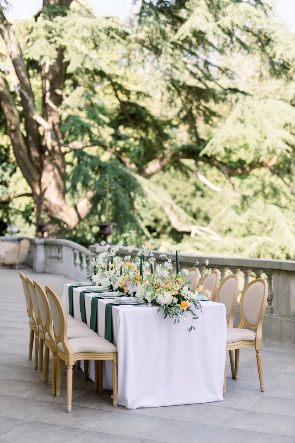 Intimate terrace tablescape at Château Bouffémont with green candles, white linens, and soft yellow floral accents.