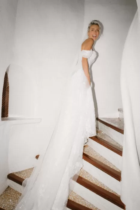 Bride smiling as she walks up the whitewashed staircase in her flowing lace gown at Hacienda Na Xamena.