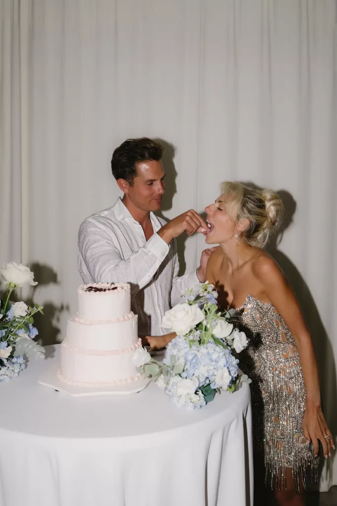 Couple laughing as they feed each other cake during the reception at Hacienda Na Xamena.