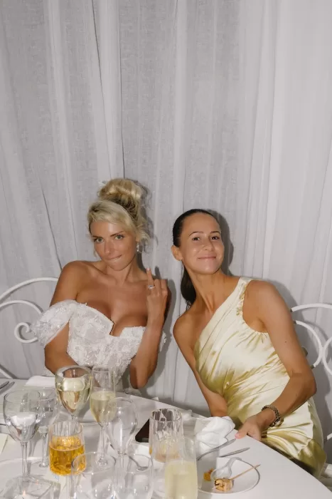 Bride and bridesmaid posing at the dinner table during the celebration at Hacienda Na Xamena.