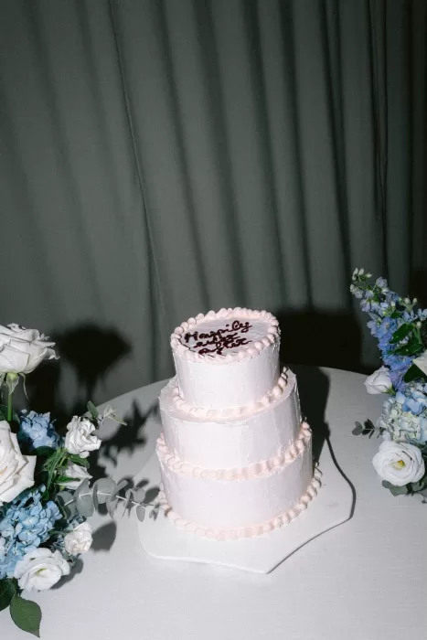 Three-tier white wedding cake surrounded by pastel florals at Hacienda Na Xamena.