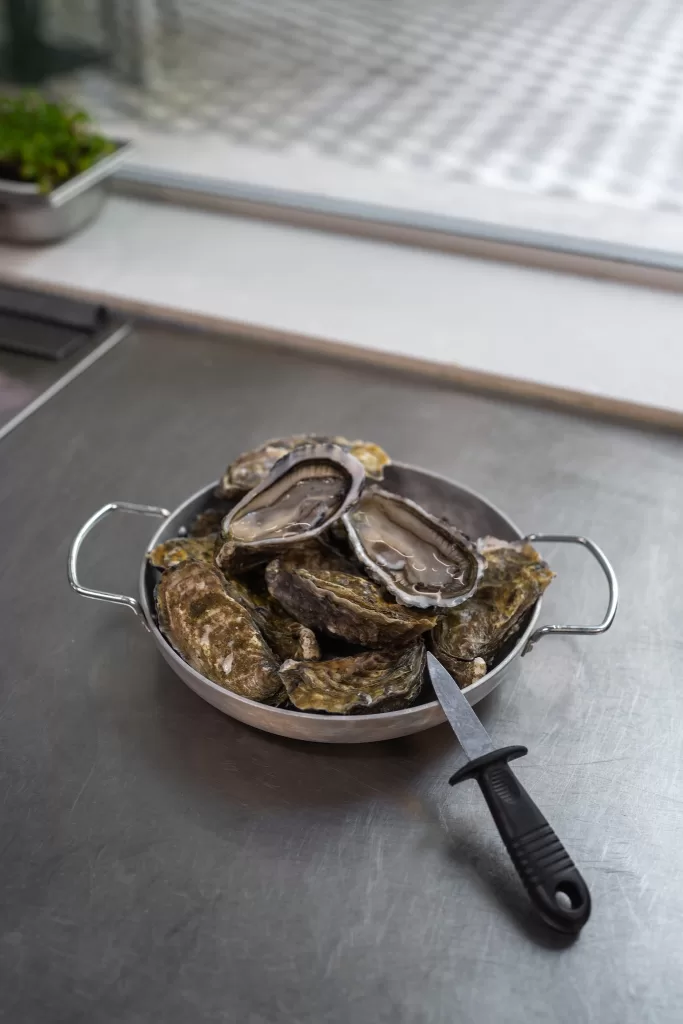 Fresh oysters prepared at Scarlett Wine & Food, Hospes Infante Sagres, displayed in a metal pan on a stainless steel counter.