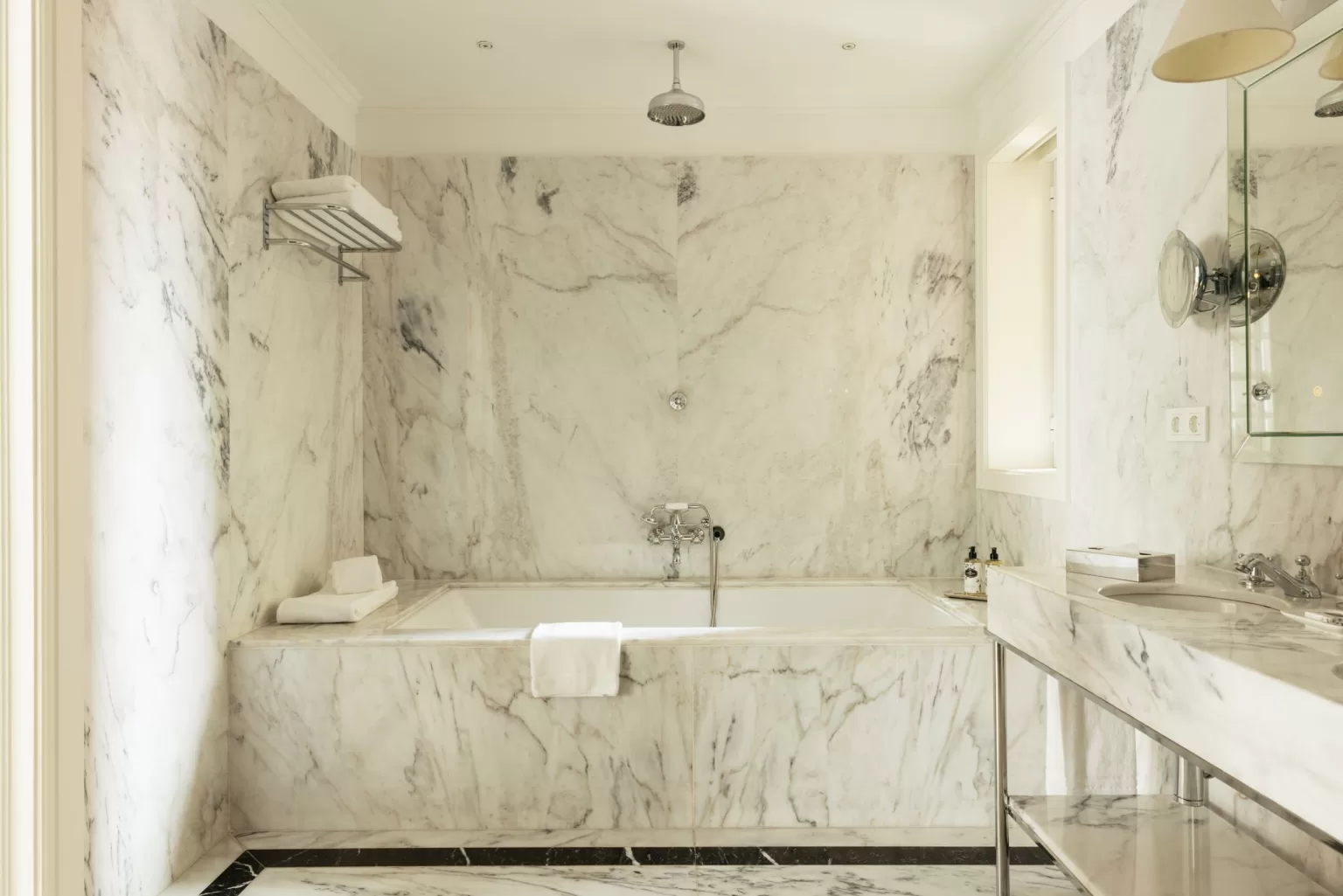 Luxurious marble bathroom at Hospes Infante Sagres with deep soaking tub, rainfall shower, and polished surfaces.