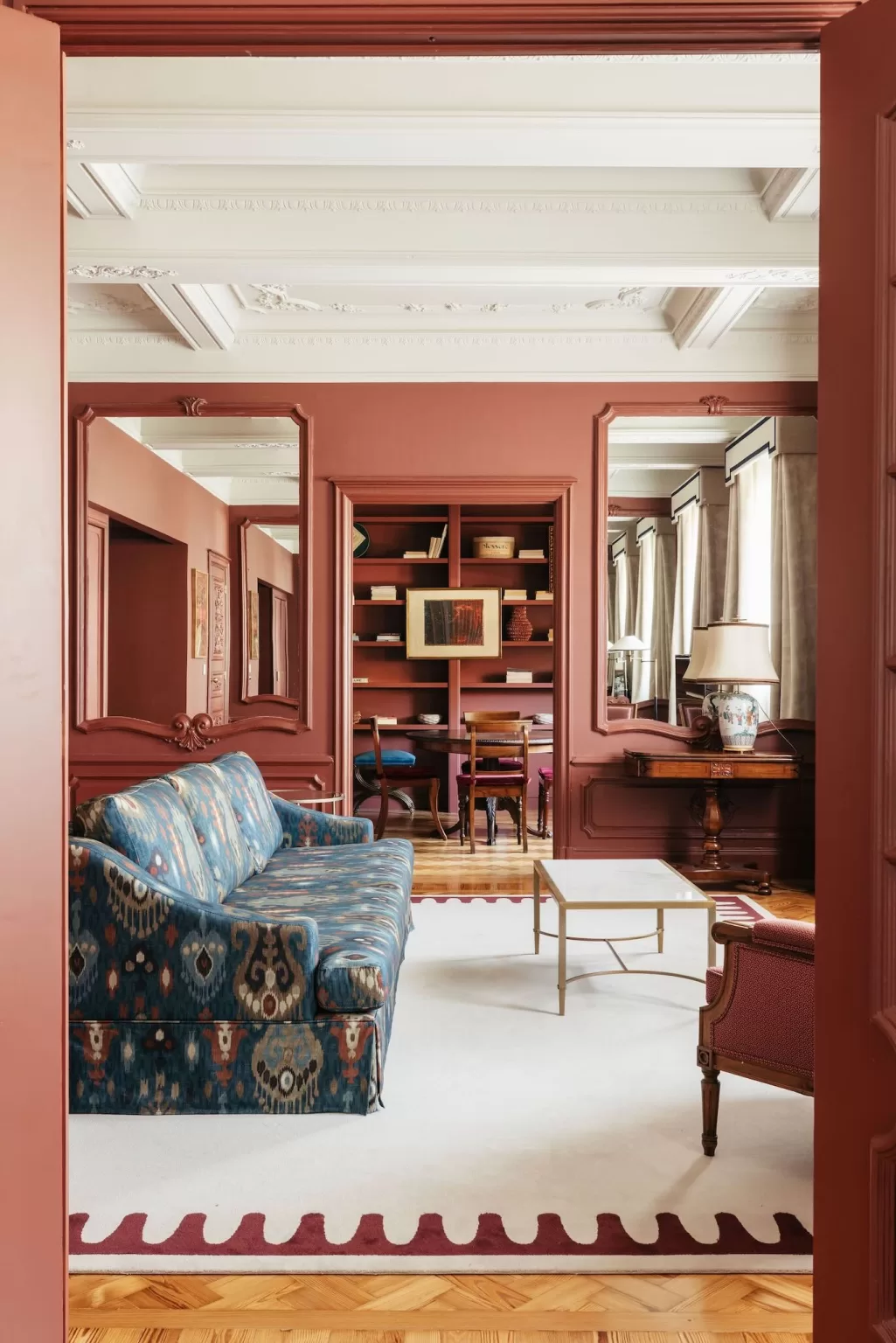 Refined suite lounge at Hospes Infante Sagres with a patterned blue sofa, warm red walls, and elegant wooden details.