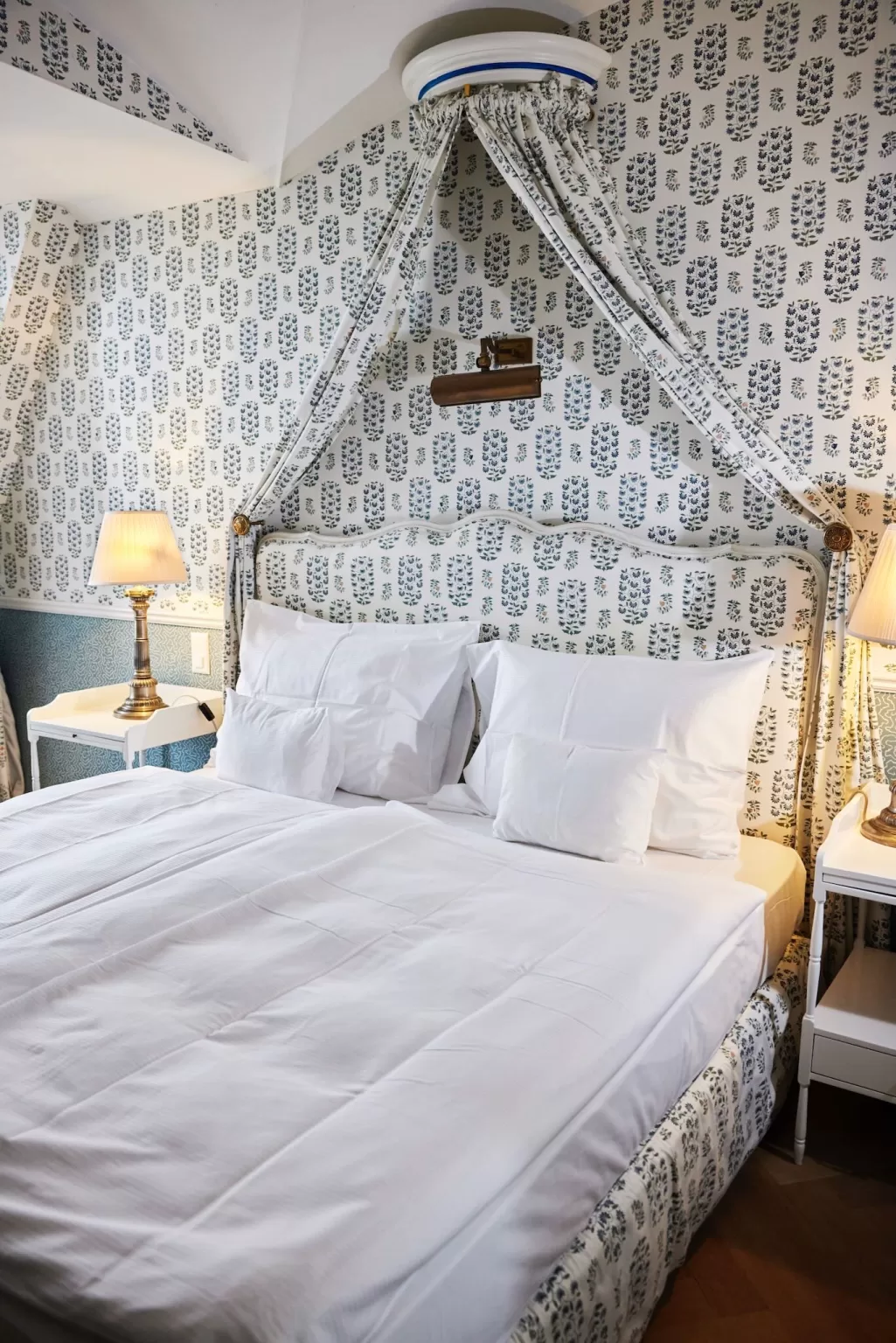 Cozy canopy bedroom at Hotel Château Gütsch with blue patterned wallpaper and soft lighting.