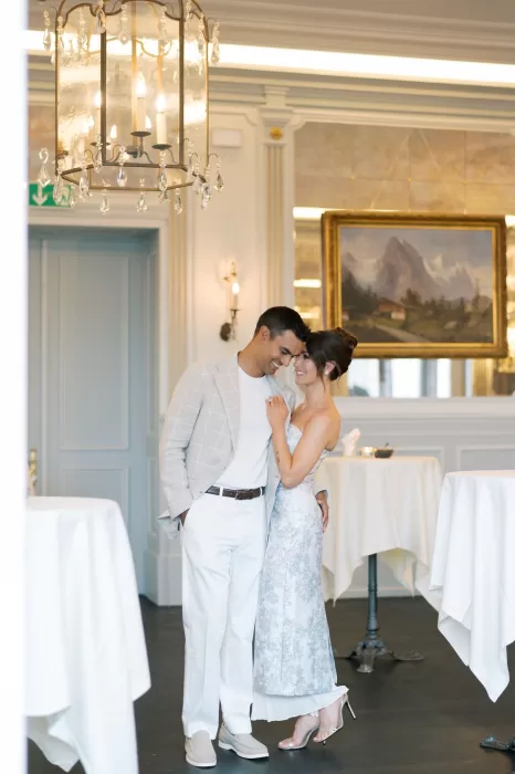Romantic moment between a couple in the elegant chandelier-lit hall of Hotel Château Gütsch.