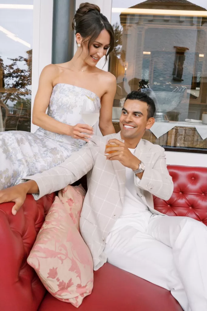 A couple enjoying cocktails together on the red leather sofas of Hotel Château Gütsch’s terrace lounge.