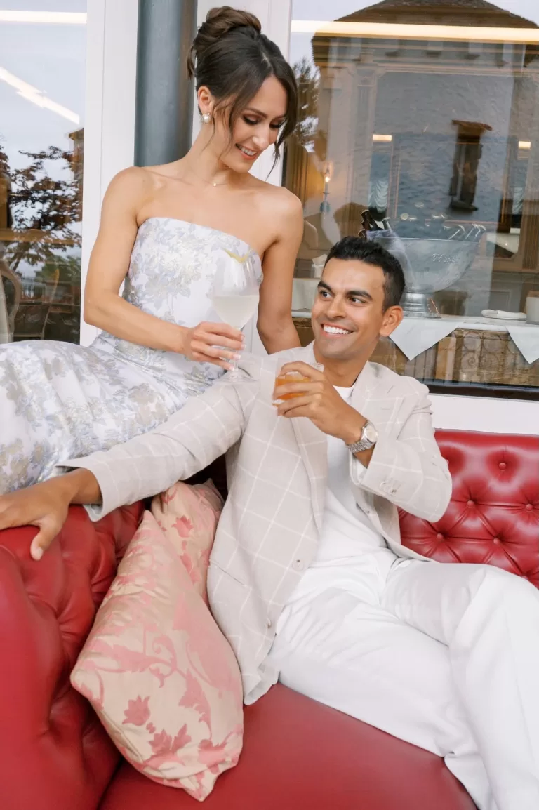 A couple enjoying cocktails together on the red leather sofas of Hotel Château Gütsch’s terrace lounge.